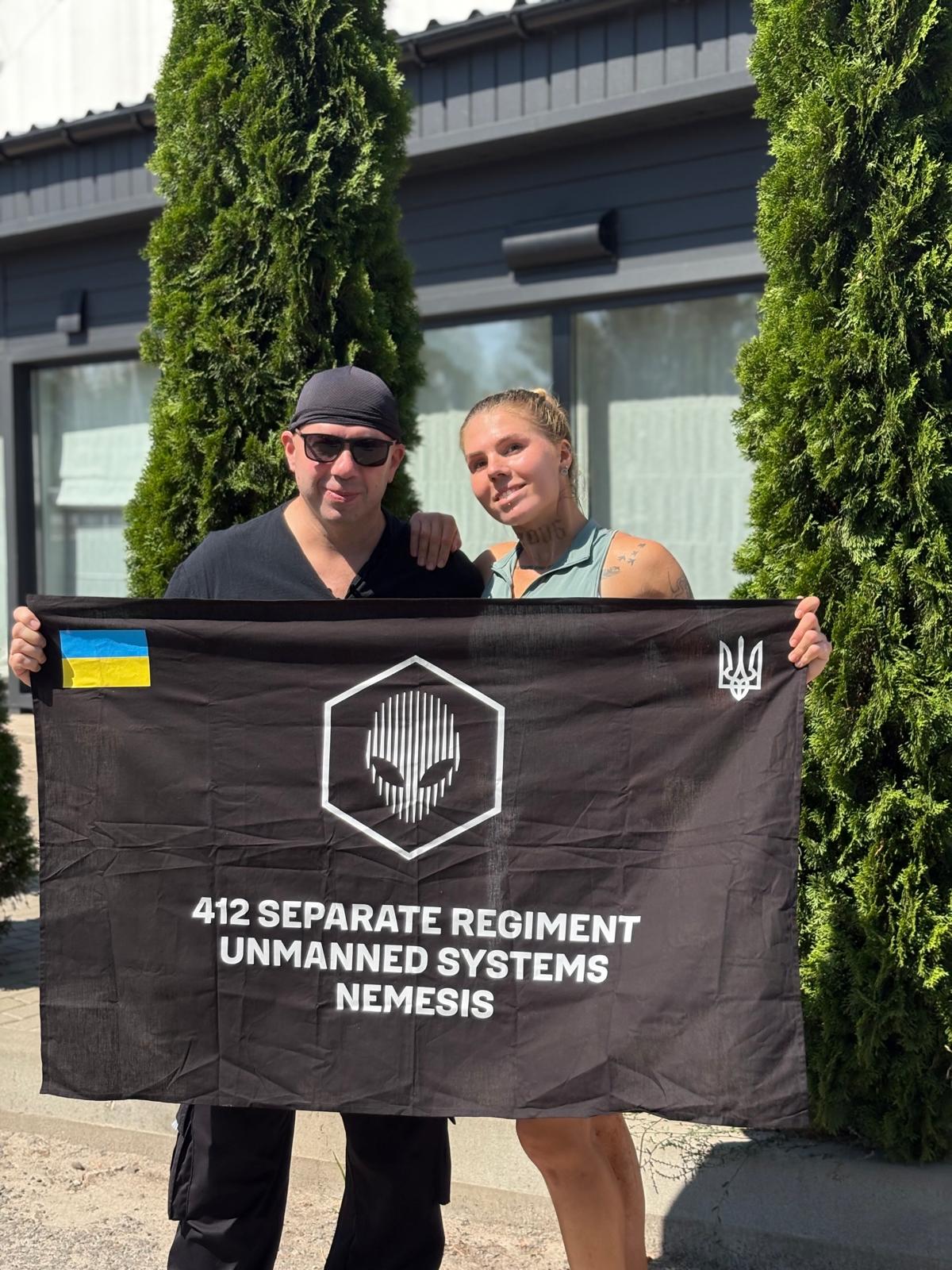 Oleksandra Oliynykova with her father and the 412th Brigade NEMESIS flag